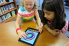 Deux enfants dans une bibliothèque scolaire faisant de l'art sur un iPad pendant le Dot Day