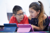 two students with iPads discuss an assignment