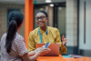 A teacher and a school librarian sit at a table in the library talking